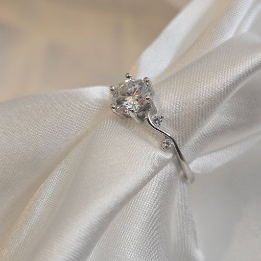 Moissanite engagement ring with twisting vine band and round brilliant-cut centre stone displayed silk sheet