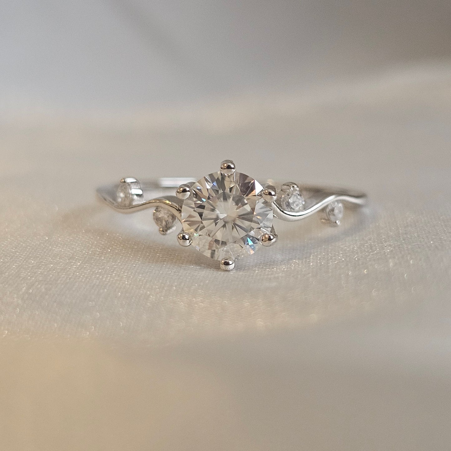 Silver ring with a 1ct moissanite diamond gemstone on a neutral background