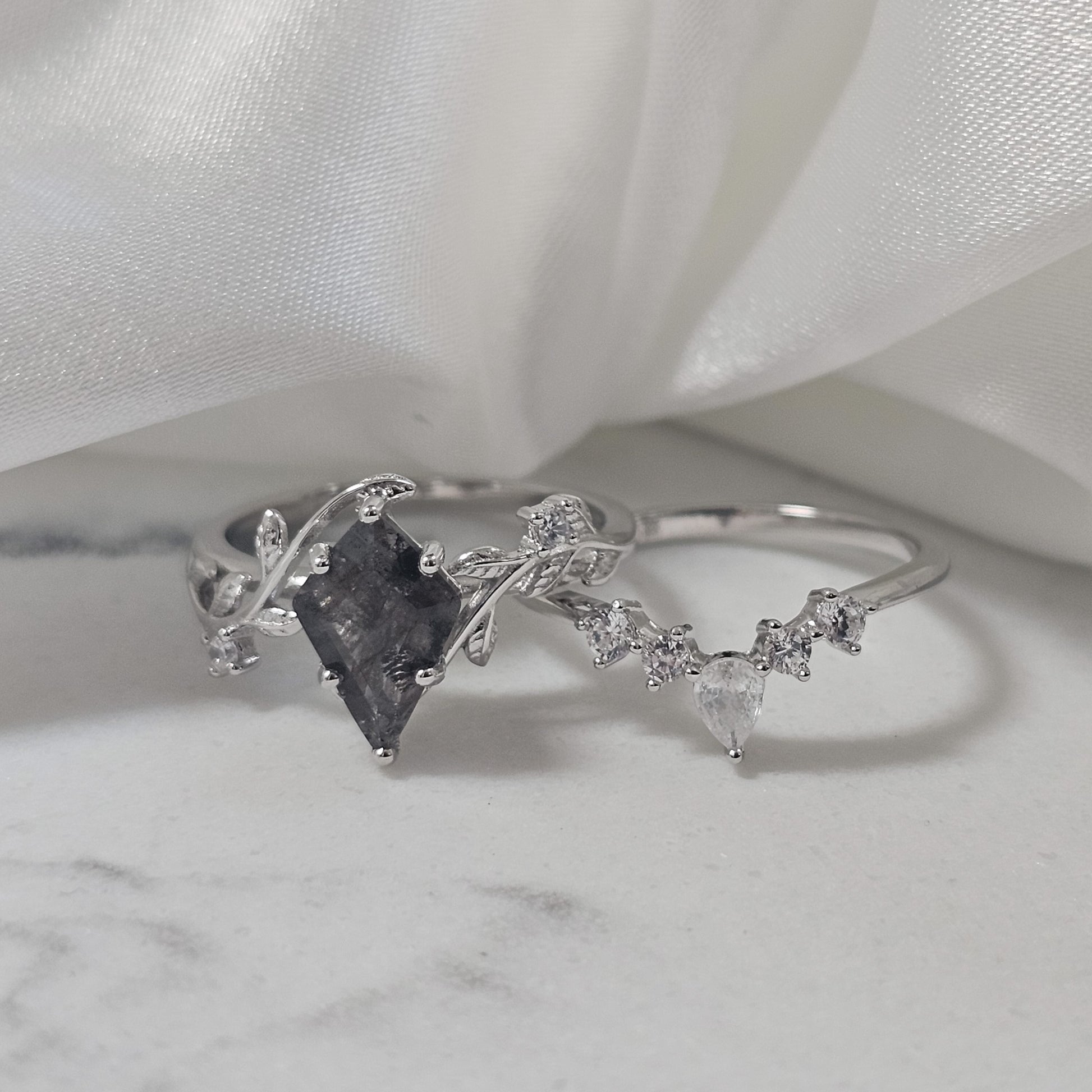 salt and pepper Herkimer diamond quartz ring set 925 silver with cubic zirconia accent stones sat on marble surface 