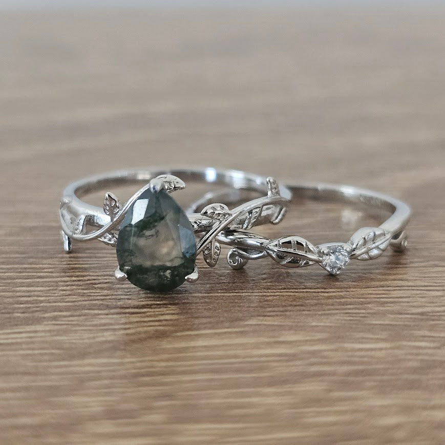 Silver ring with a dark gemstone on a wooden surface