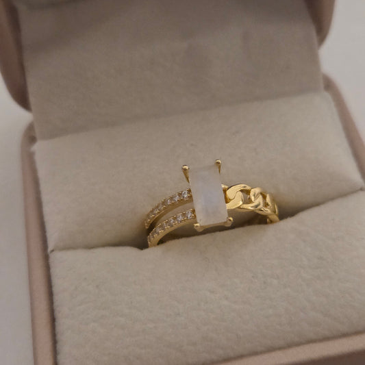 Gold ring with a white moonstone stone on beige fabric