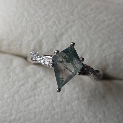 Silver ring with a green gemstone on a textured surface