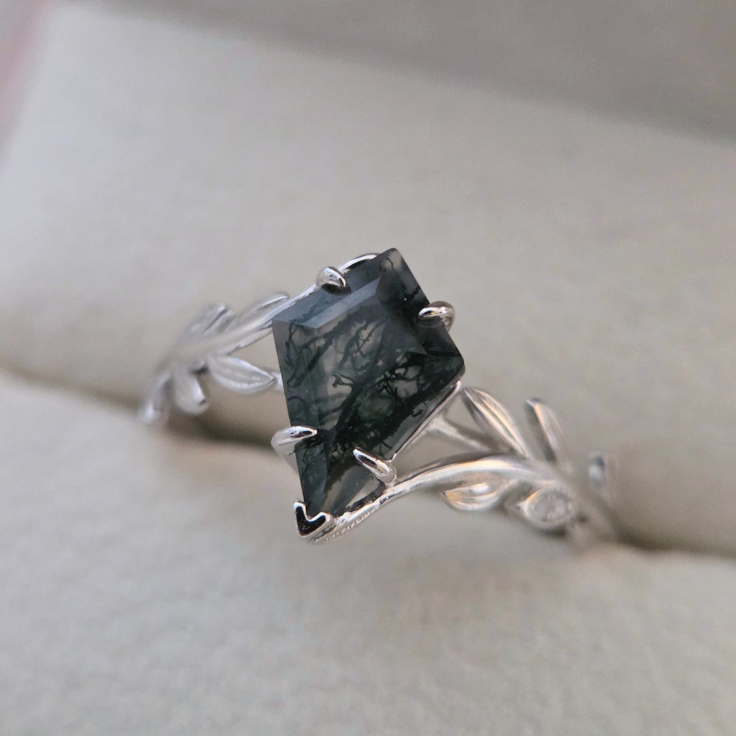 Olive Grove natural moss agate ring set in 925 sterling silver with platinum plating, featuring a square-cut green moss agate stone and leaf-inspired band on a soft neutral background