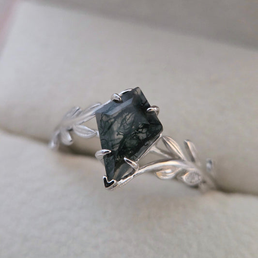 Olive Grove natural moss agate ring set in 925 sterling silver with platinum plating, featuring a square-cut green moss agate stone and leaf-inspired band on a soft neutral background