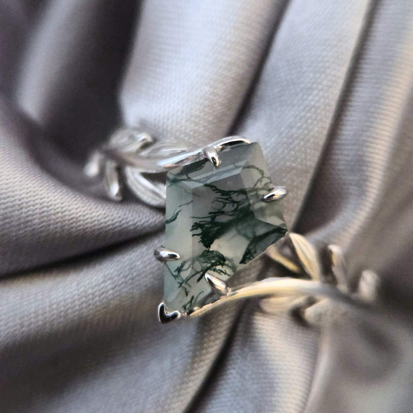 Olive Grove natural moss agate ring set in 925 sterling silver with platinum plating, featuring a square-cut green moss agate stone on a soft grey fabric background