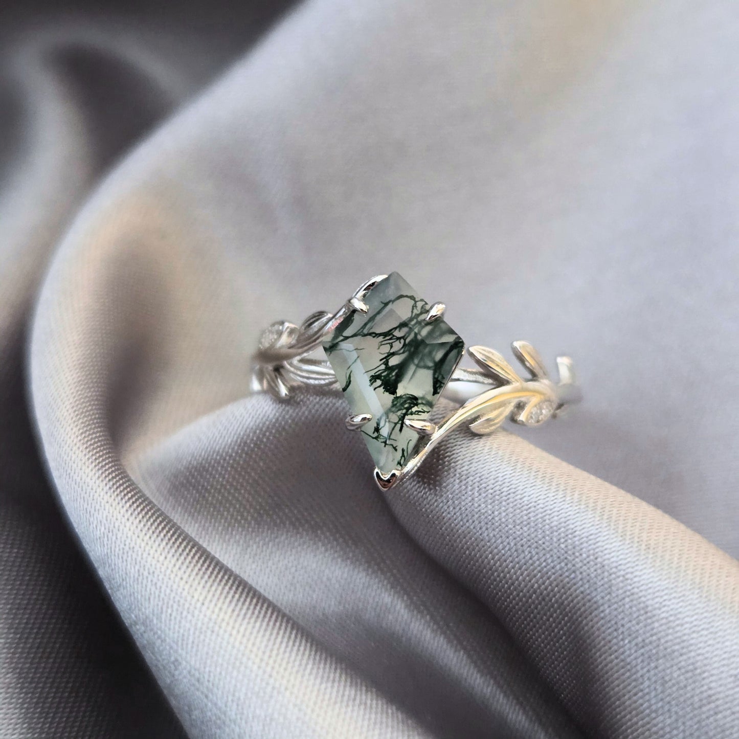 Olive Grove natural moss agate ring in 925 sterling silver with platinum plating, featuring a square-cut moss agate stone and leaf-inspired band on soft flowing fabric