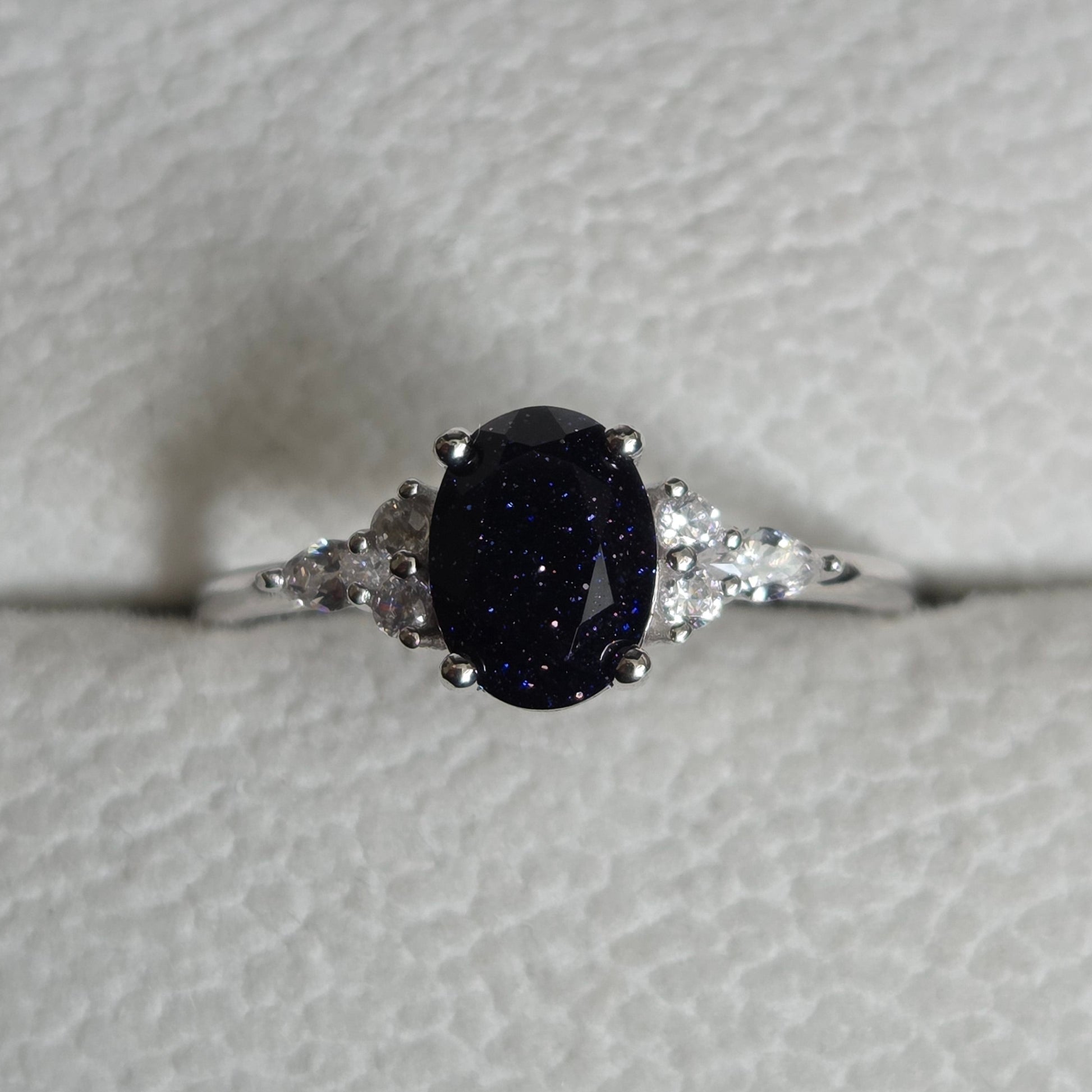 Silver ring with a dark gemstone on a light gray background