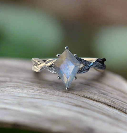 Silver ring with a large gemstone on a woodland surface