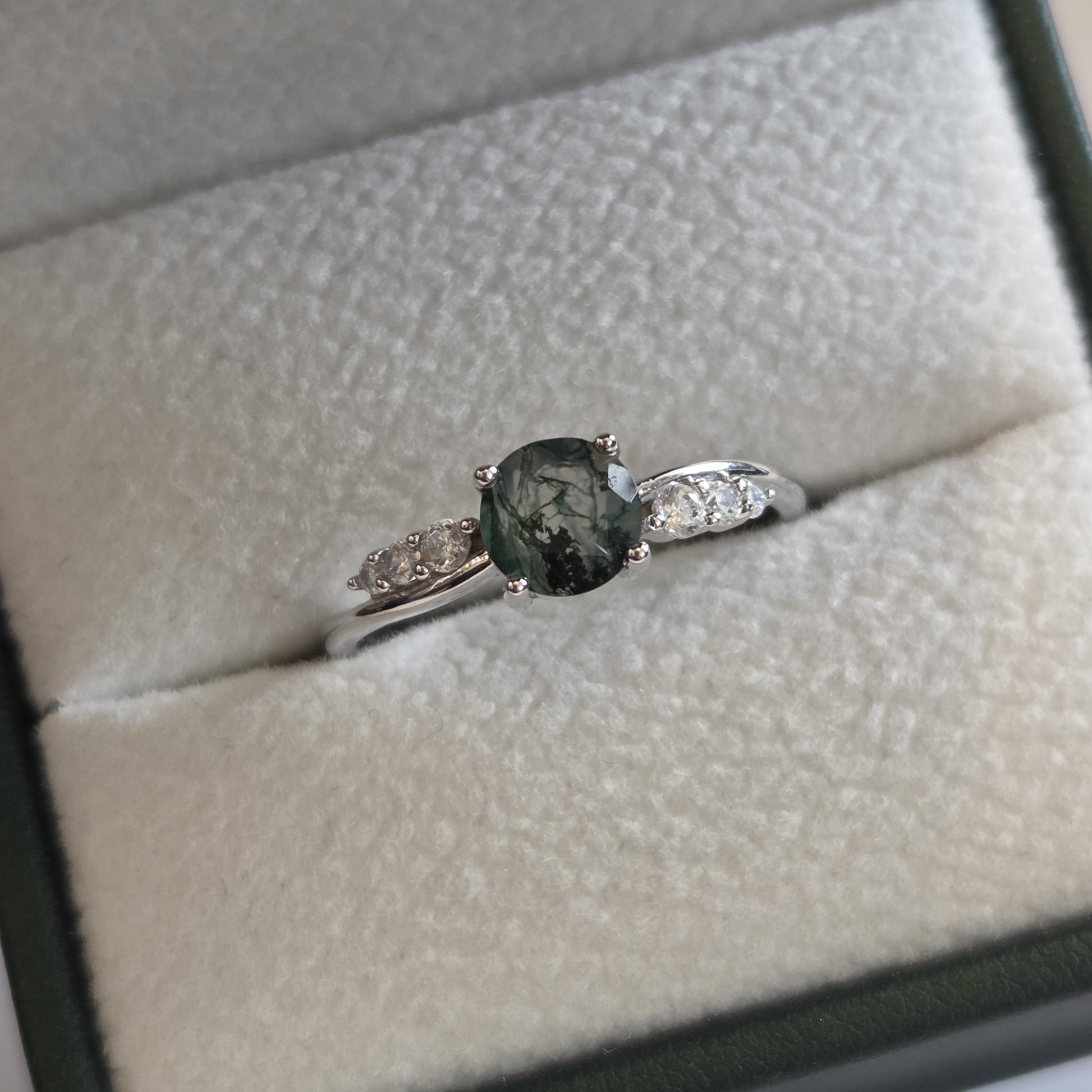Natural moss agate ring with an oval moss agate gemstone and sparkling cubic zirconia accents, displayed in a jewellery box. Crafted in 925 sterling silver and inspired by the beauty of nature.