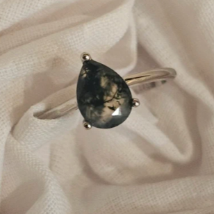 silver ring with a pear-shaped gemstone on a beige fabric background