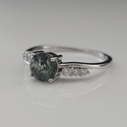 Side view of a natural moss agate ring featuring an round moss agate gemstone with cubic zirconia accent stones, crafted in 925 sterling silver and photographed against a soft white background.