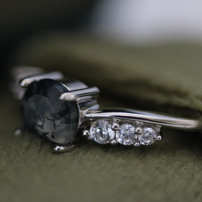 Macro close-up of a natural moss agate ring showing the moss agate gemstone and sparkling cubic zirconia accent stones, crafted in 925 sterling silver and displayed in a green velvet jewellery box.