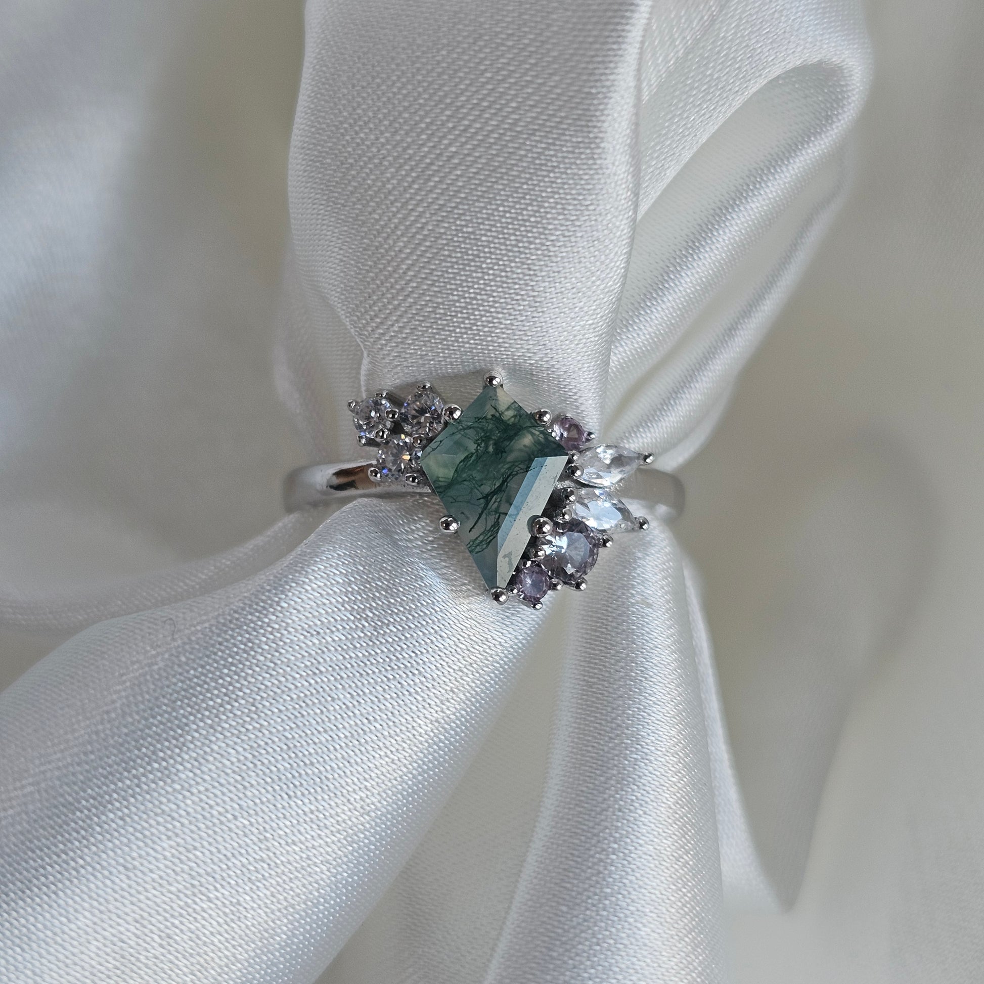 Silver ring with a green moss agate gemstone with alexandrite accent stones on white silk fabric