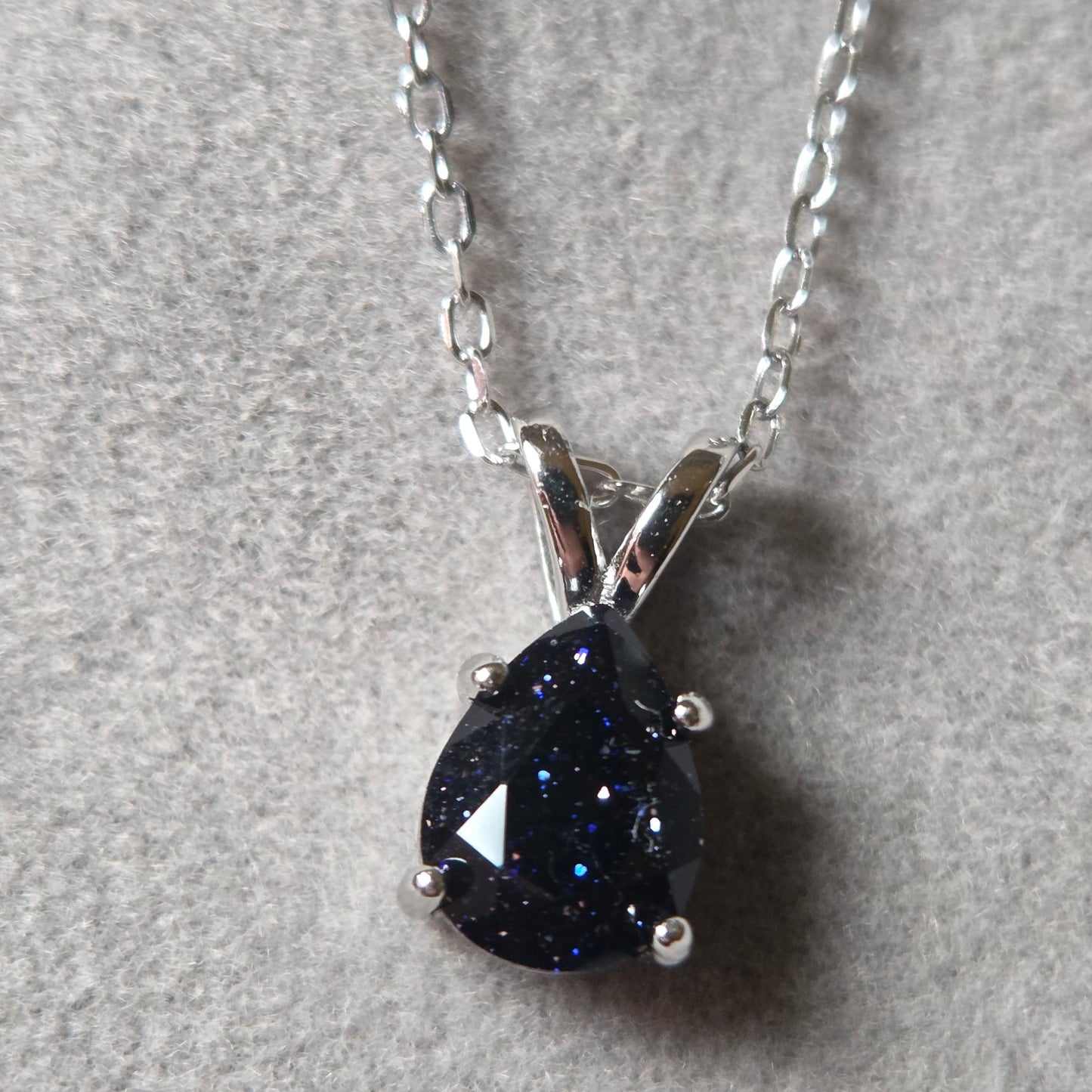 Silver necklace with a black teardrop-shaped pendant on a gray background