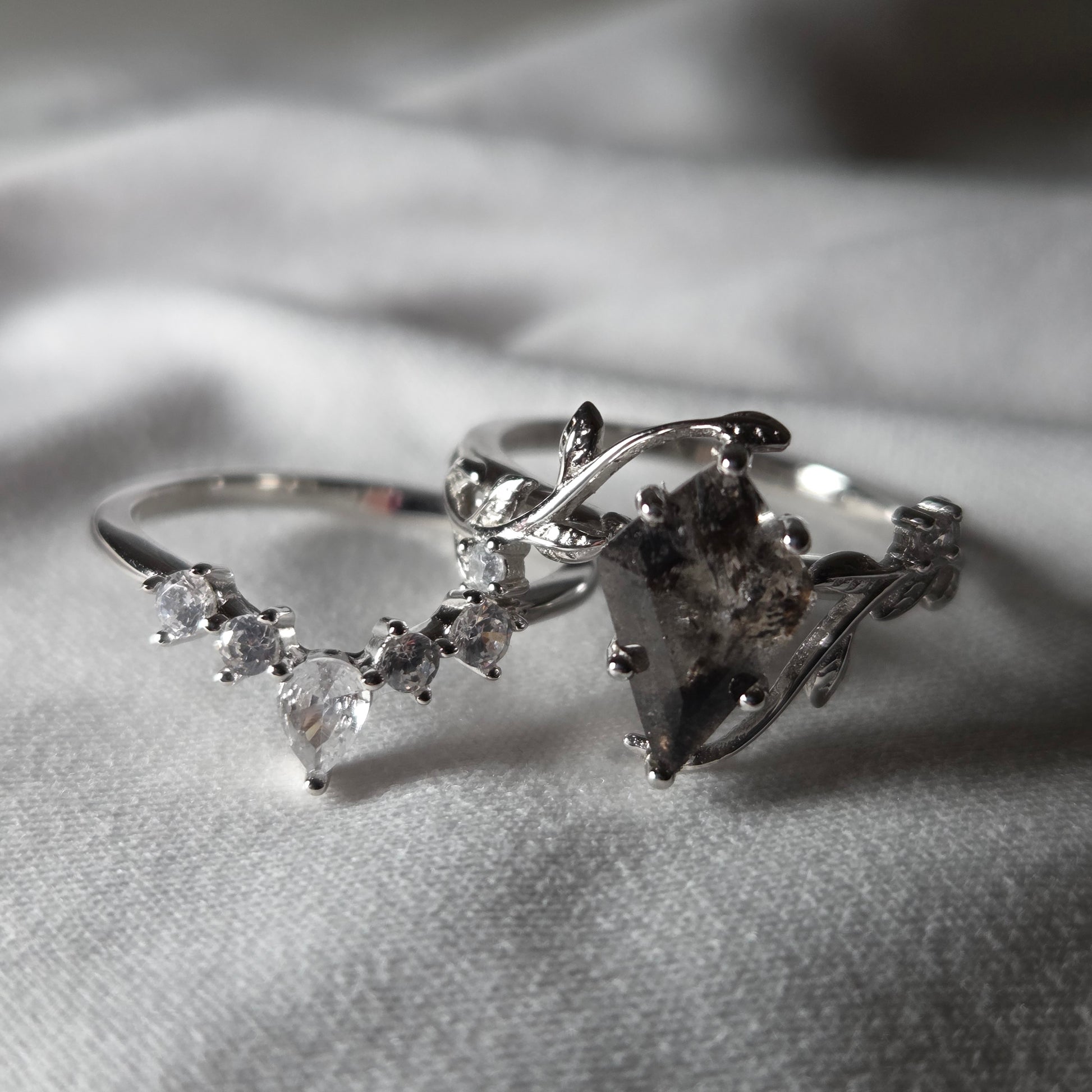 Silver ring with diamond accents on a soft gray background