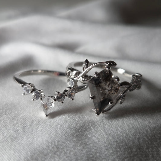 Silver ring with diamond accents on a soft gray background