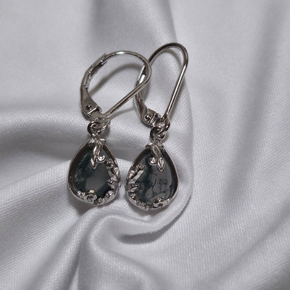 Pair of silver earrings on a white fabric background moss agate earrings dangle