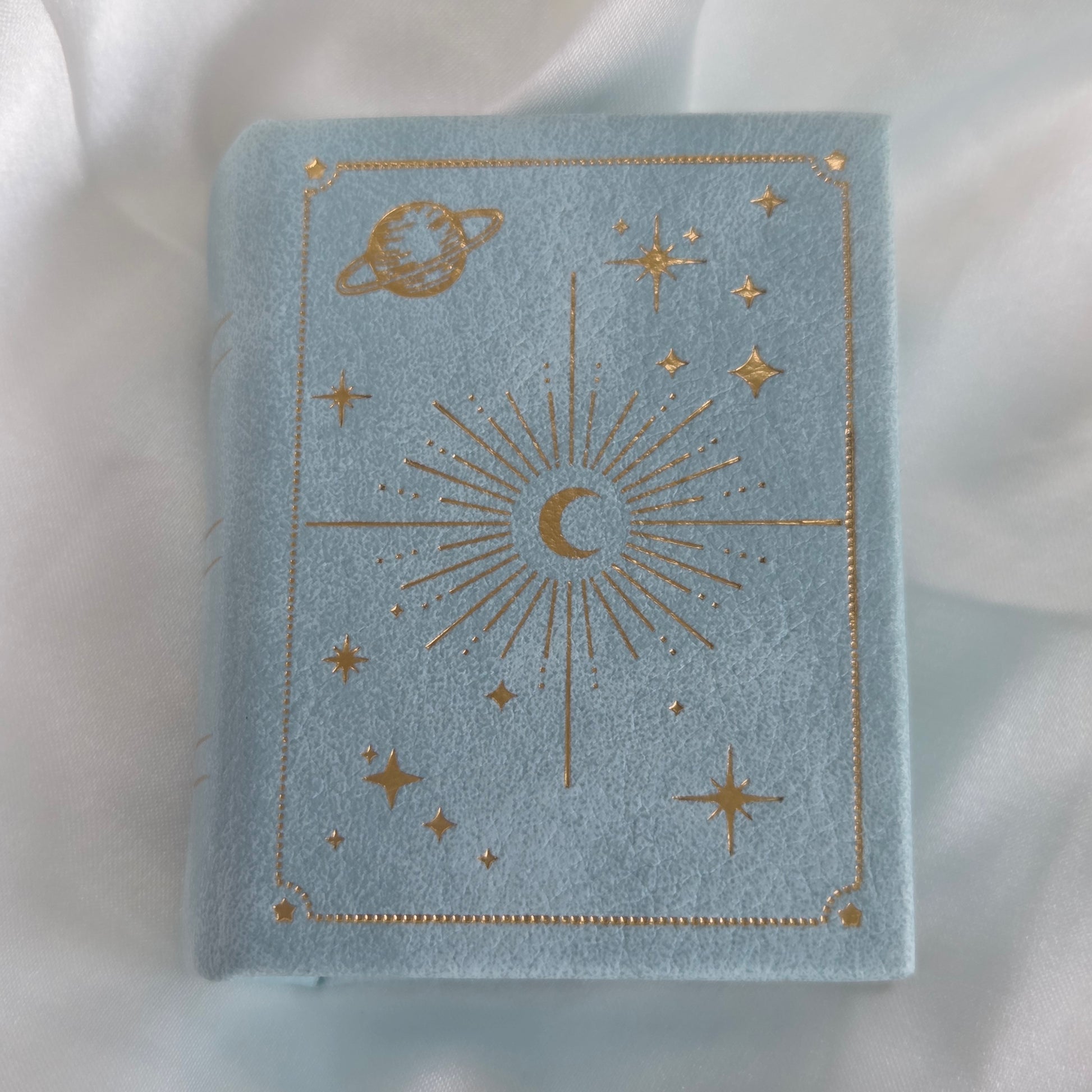 Blue velvet jewelry box with gold celestial designs on a white background