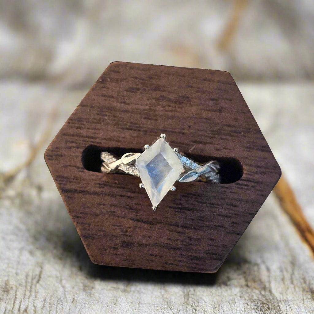 Kite shaped moonstone ring in a wooden ring holder on a wooden background
